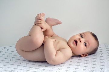 naked baby lying on his back on the diaper