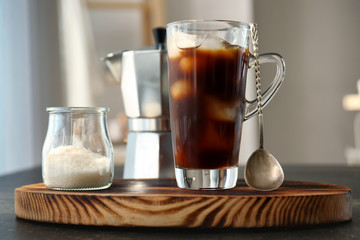 Glass cup with cold brew coffee and sugar bowl on cutting board