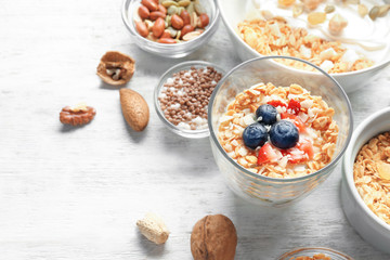 Tasty desserts with yogurt in glass and bowl on table