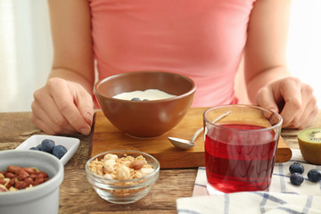Woman eating tasty yogurt at table