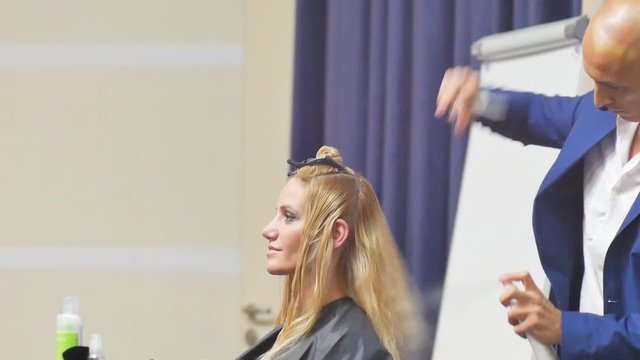 Stylist man cuts hair blonde Italian in a hairdressing salon