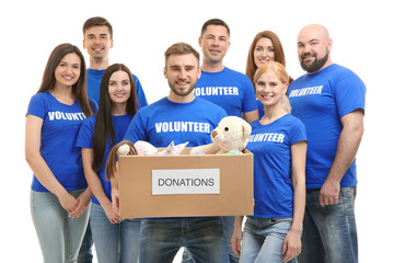 Young volunteers with box of donations on white background