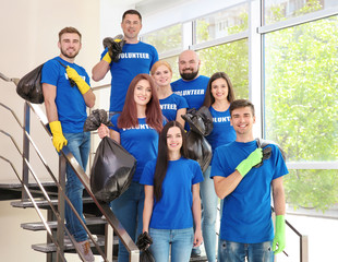 Young volunteers with garbage bags on staircase