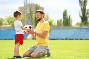 Dad and son with soccer ball in stadium