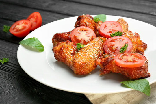 Plate with delicious chicken wings on kitchen table