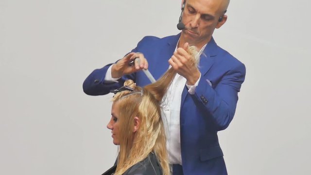 Stylist man cuts hair blonde Italian in a hairdressing salon