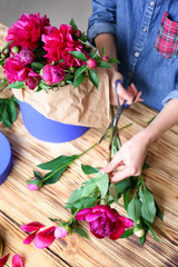 Fototapeta na wymiar Female florist making bouquet of beautiful peonies in flower shop