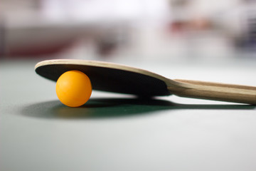 Orange ping pong ball and paddle shallow depth of field 