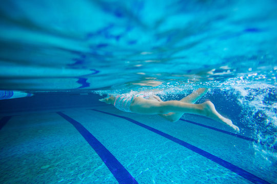 Young girl swimming underwater in pool