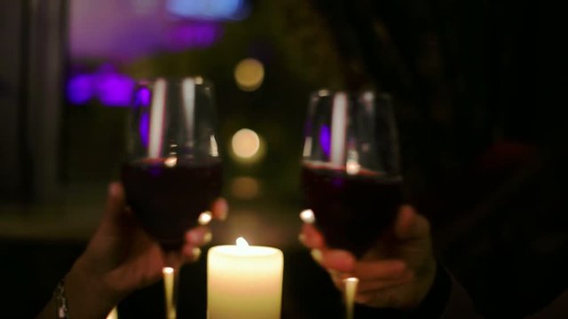 Couple in love holding hands and clink glasses during a romantic dinner.