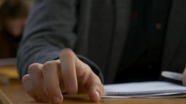 Student hand finger tapping closeup. Young man taps his fingers on a table