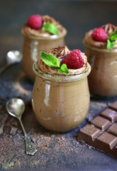 Chocolate mousse with fresh raspberry and mint in a vintage glass jar.