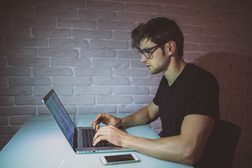 Handsome young programmer working at home late in evening