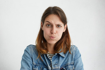 Headshot of displeased European woman blowing her cheeks being upset raising her eyebrows,...