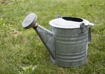 an old metal watering can in grass