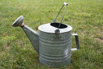 an old metal watering can in grass