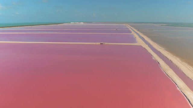 AERIAL: Flying above the gorgeous pink-colored lakes of Las Coloradas. Spectacular view over the red, orange and purple brightly colored salt ponds stretching across the shore of the Gulf of Mexico