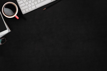 Modern dark surface office desk table with computer, office supplies and cup of coffee.