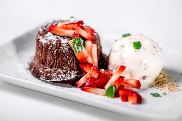 Chocolate cake with powder sugar, ice cream and strawberries