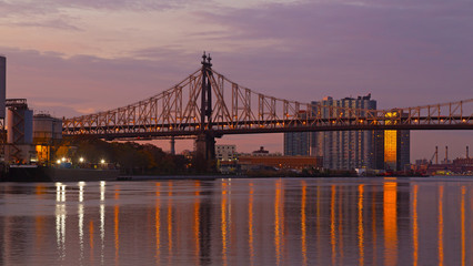 Fototapeta na wymiar Ed Koch Queensboro Bridge over East River at sunrise in New York City, USA. A view on scenic sunrise over the bridge from Roosevelt Island.
