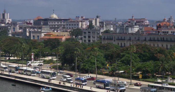 A slowly moving aerial dolly establishing shot of traffic and buildings on the El Malecón in downtown Havana, Cuba.  	