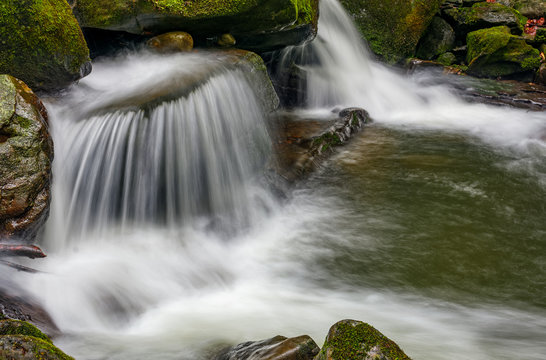 small cascade on the river among bouders in forest