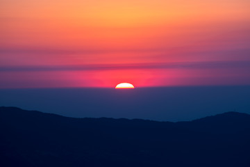 Obraz premium sun behind mountain layer during chage of light
