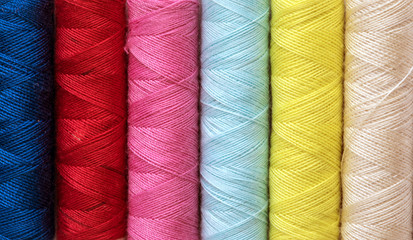 Close up multi color of the bobbins threads roll as background