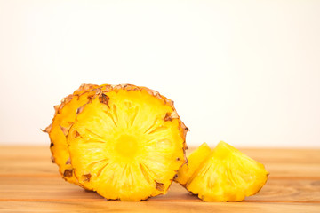 The pineapple whole bulb with  sliced pineapple fruit on wooden table with white background , tropical summer fruit  concept
