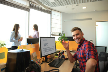 Handsome businessman in casual wear on background of his partners in the creative office.