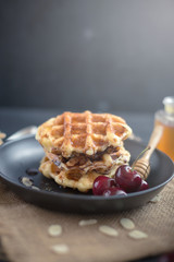 Honey on waffles with cherry berries on dark wooden background. breakfast concept
