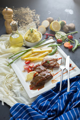 Fresh grilled meat. Grilled beef steak on white plate French fries and Mashed potato with spoon, in serving bowl