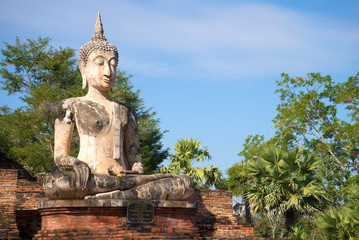 Ancient sculpture of a seated Buddha on the ruins of the Buddhist temple of Wat Mae Chon in Sukhothai, Thailand