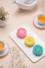 Sweet color of snow skin mooncake. Traditional mid autumn festival foods with tea on table setting.
