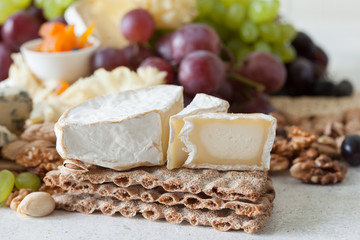 Cheese plate served with grapes, jam, cured melon, crackers and nuts