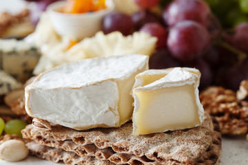 Cheese plate served with grapes, jam, cured melon, crackers and nuts