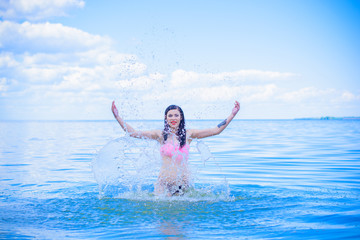 A wet beautiful sexy young woman bathes in the blue water, showing off her beauty. The concept of female beauty, sports figure and healthy lifestyle