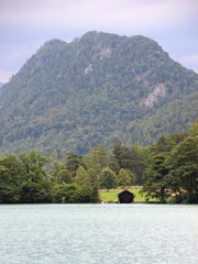 Fototapeta premium Boathouse with Mountain Background at Blue Water Sea