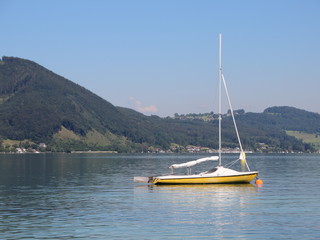 Yellow Sailboat on Blue Lake with Mountain Background