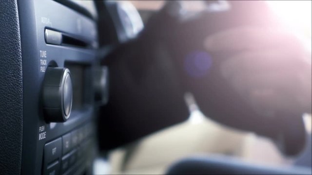 Close-up of female hand adjusting button audio on a vehicle's dashboard.