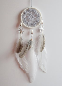 Photo of handmade dreamcatcher with feathers and beads on a white background