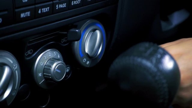 Close-up of female hand adjusting button control air conditioning on a vehicle's dashboard. Slowmotion shot