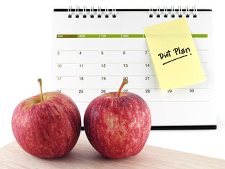 two apples and monthly diet plan reminder note message attached on desk calendar, planning to lose weight by healthy eating concept