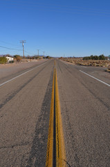 Center view of the famous Road 66 with straight yellow middle line and electric poles