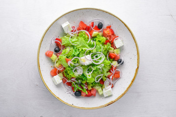 Greek salad of fresh vegetables and cheese. On a wooden background. Top view. Free space for your text.