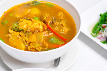 Close-up red curry with chicken in white bowl and white background