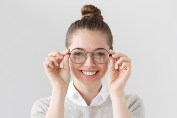 Closeup of attractive young woman isolated on gray background, wearing big round spectacles with...