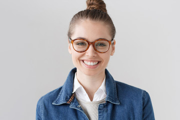 Indoor portrait of beautiful university student girl wearing horn-rimmed spectacles and denim...
