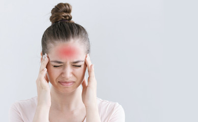 Fototapeta premium Portrait of female isolated on grey background suffering from severe headache, pressing fingers to temples, closing eyes in order to relieve pain