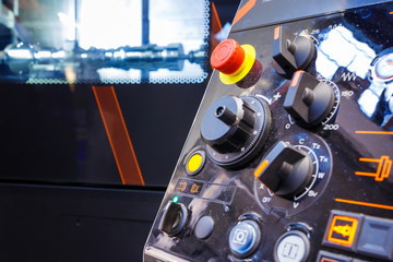 Close up of control panel of CNC machine with adjustment controls and push buttons. Selective focus.